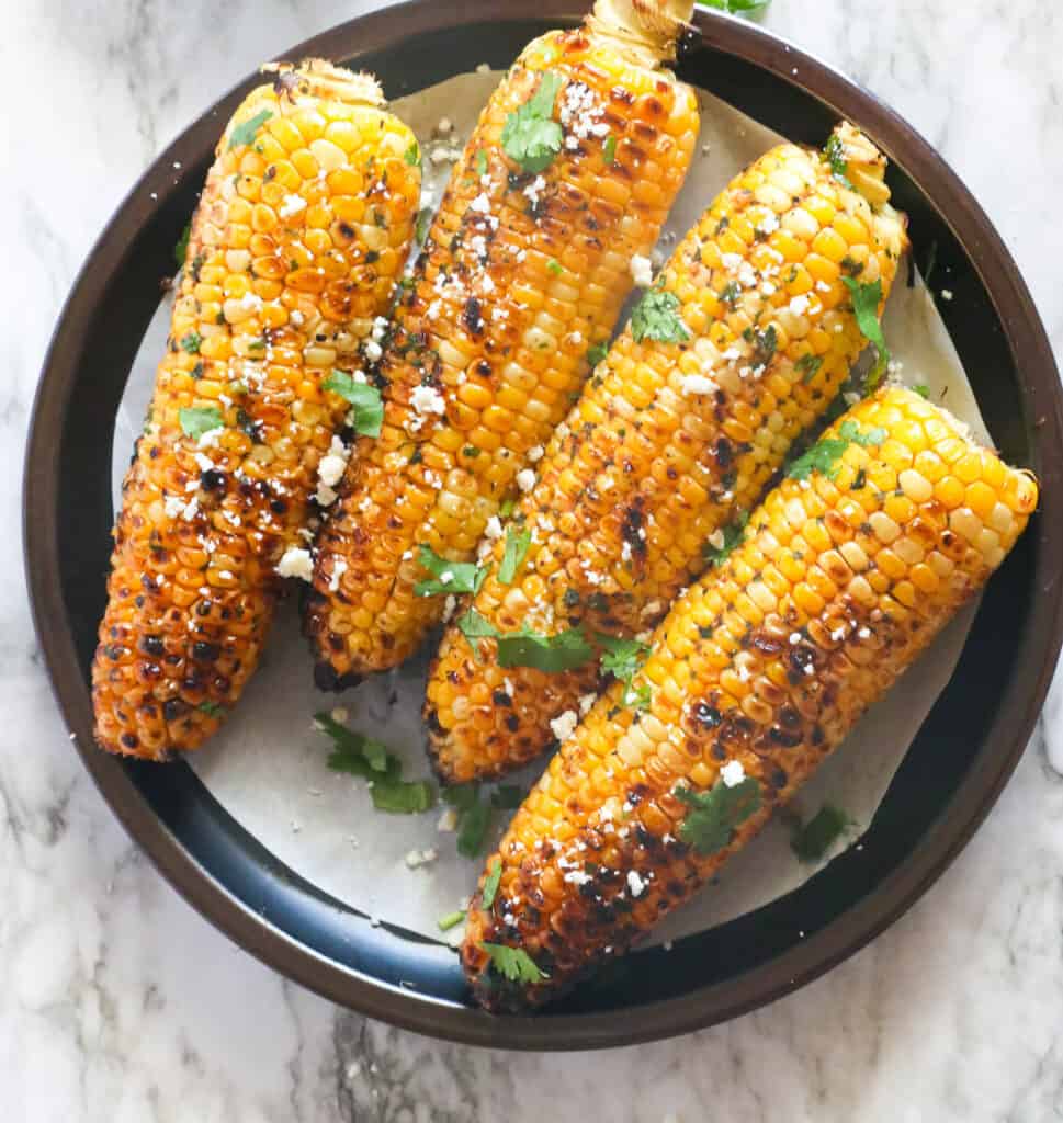 A plateful of grilled corn sprinkles with cilantro and queso fresco