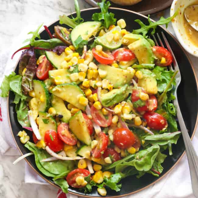 A bowl of avocado corn salad with a fork