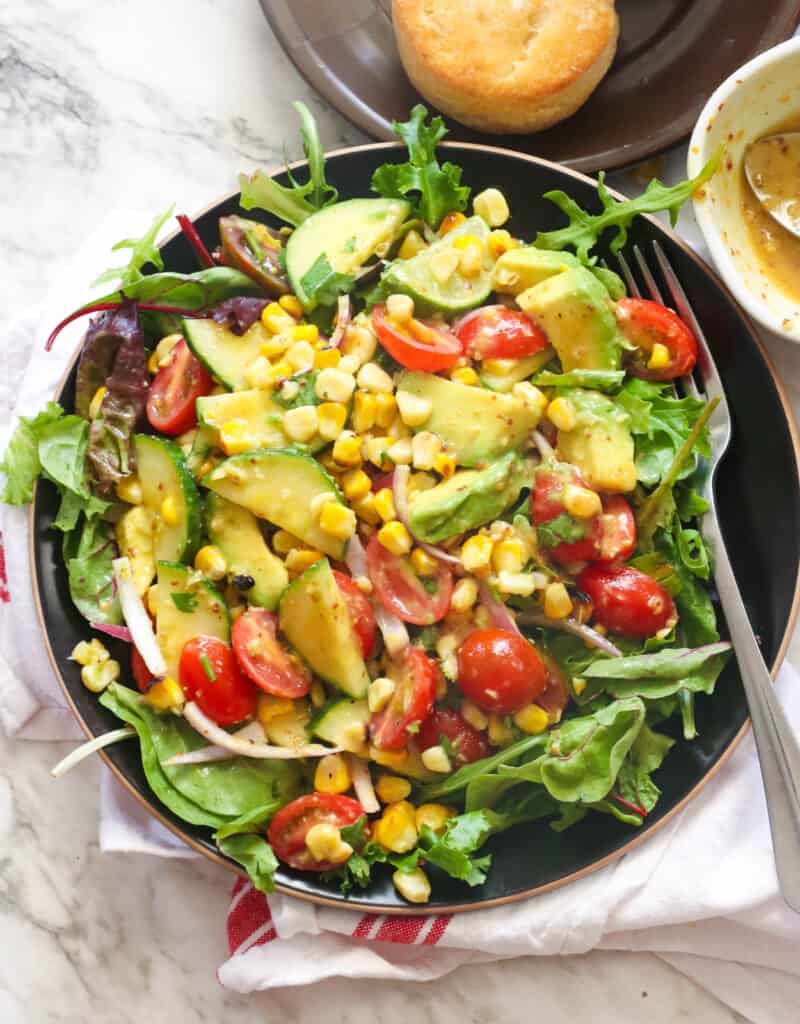 A bowl of avocado corn salad with a fork