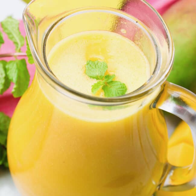 A pitcher of mango muice garnished with mint