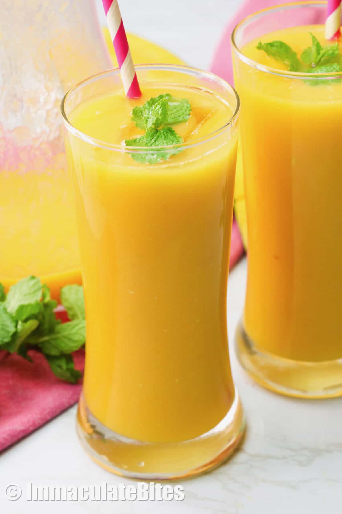 Two glasses of mango juice garnished with mint