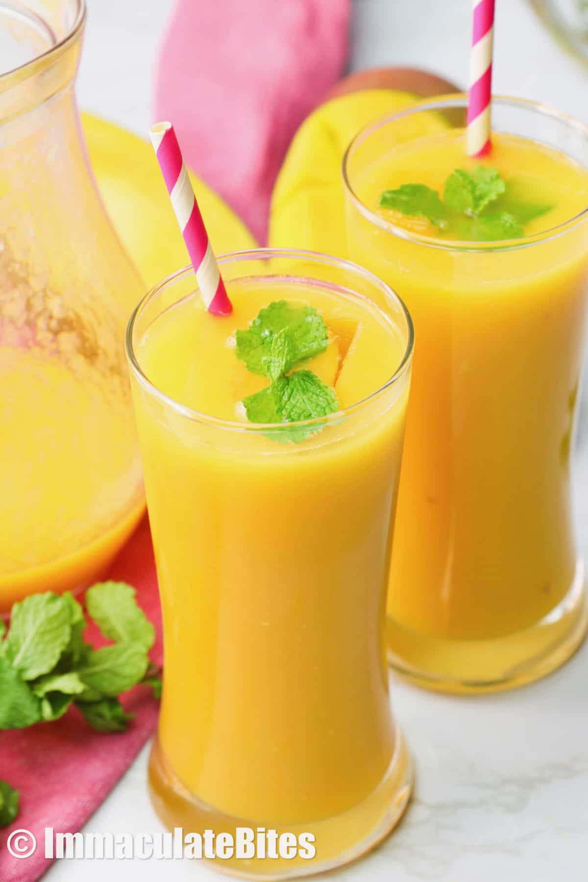 Two glasses of mango juice garnished with mint leaves