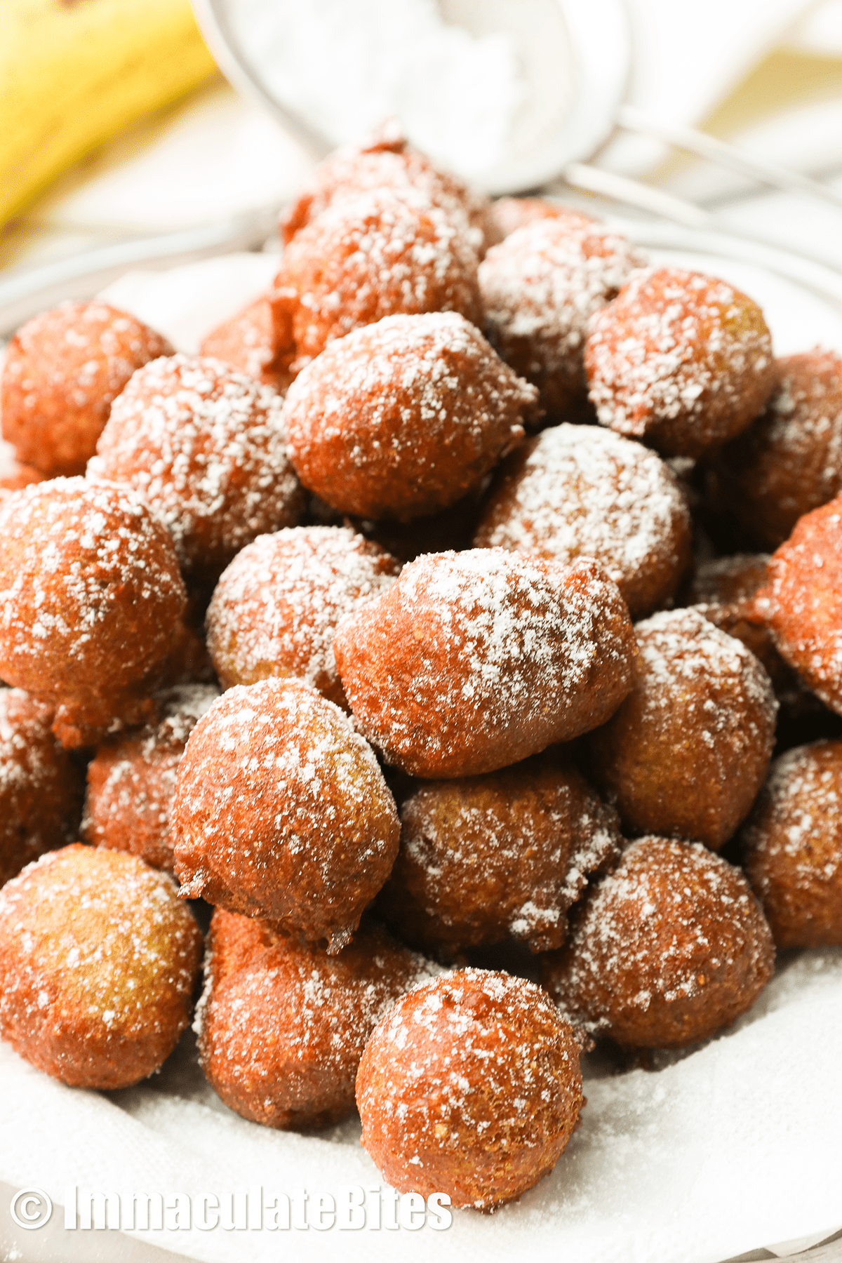 A pile of banana fritters dusted with powdered sugar