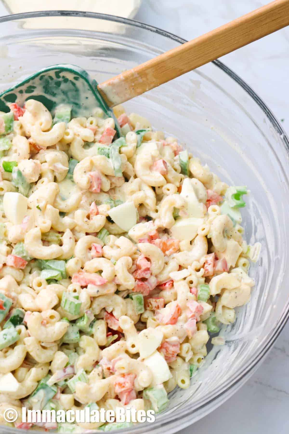 A bowl of macaroni salad in a clear bowl