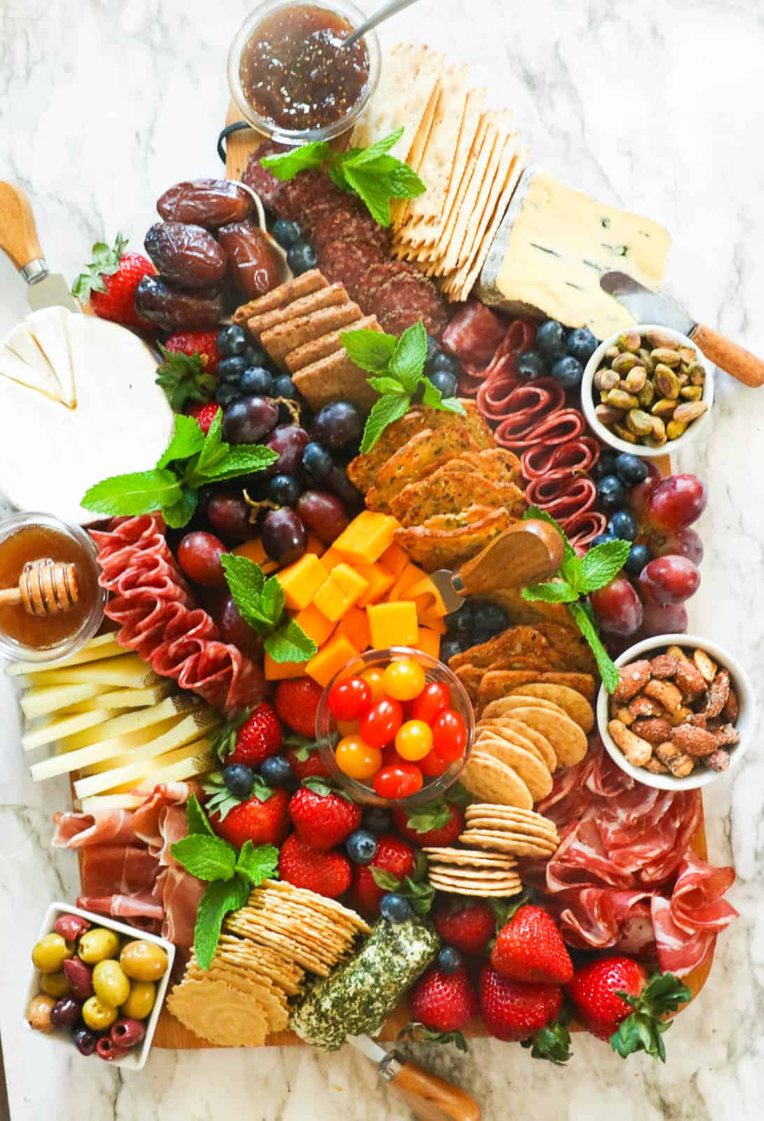 Charcuterie board with crackers, meats, fruits, and spreads