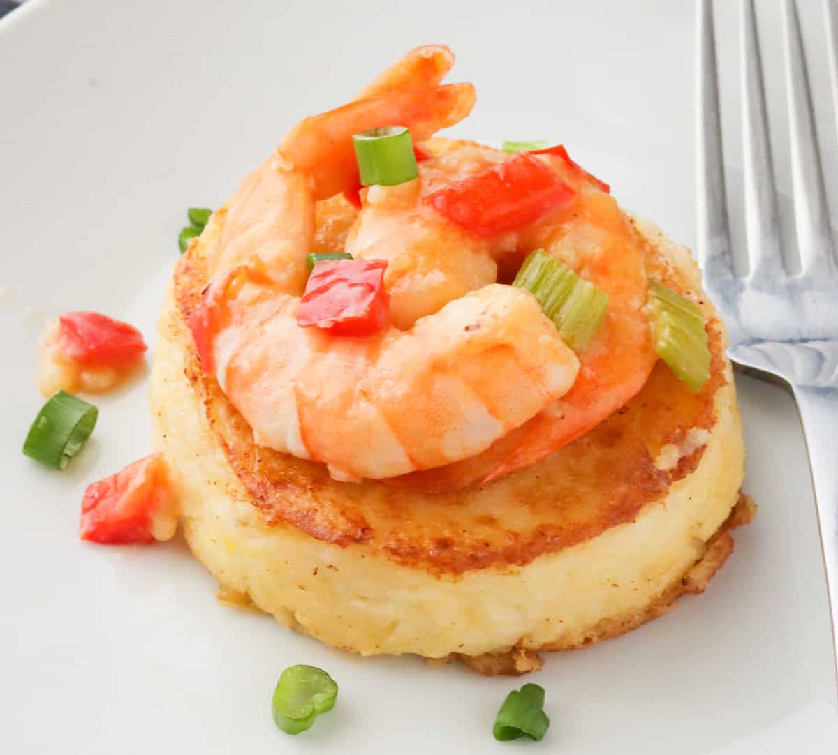 a grit cake topped with shrimp and other toppings