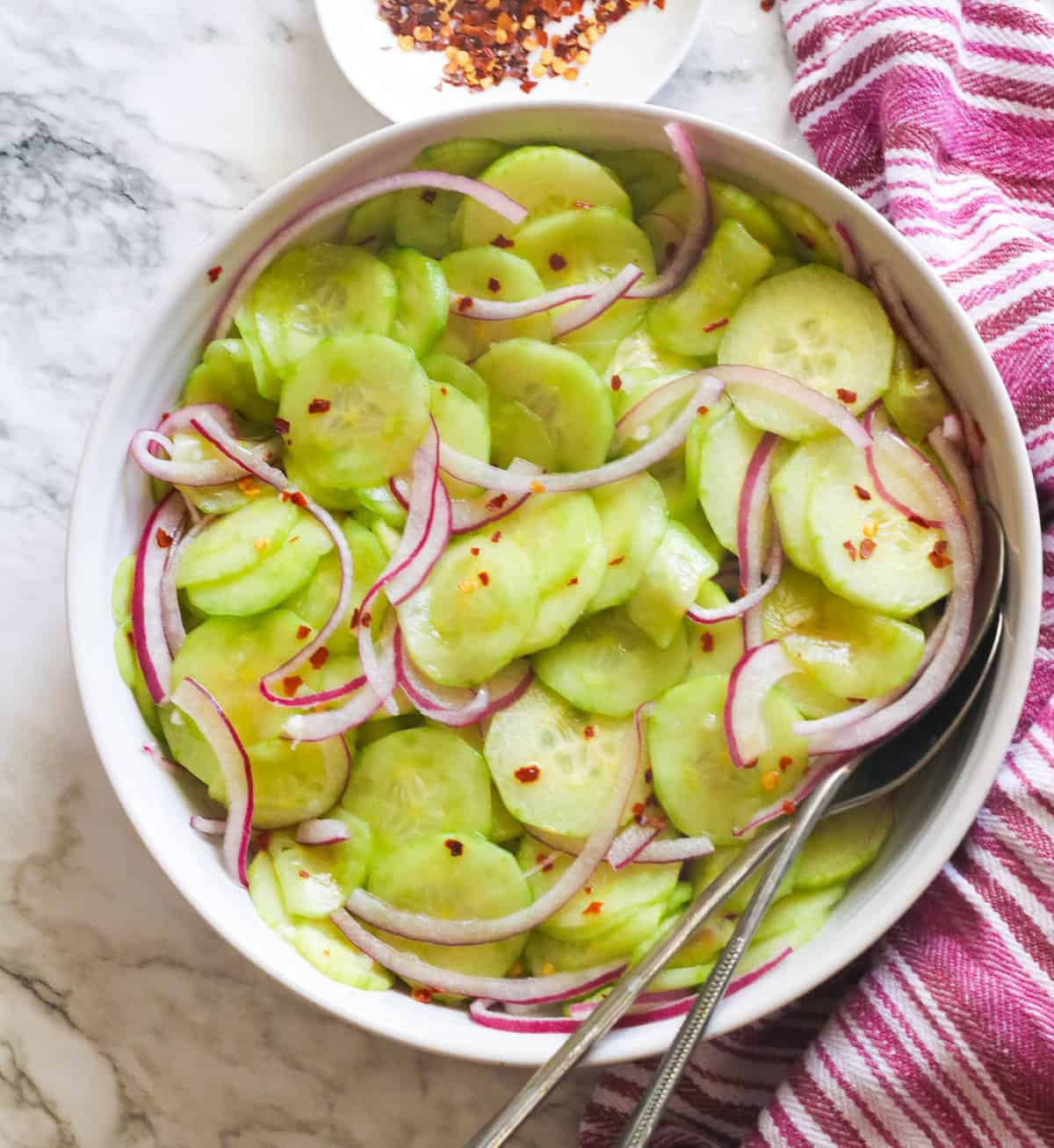 Cucumber and onion salad in a white bowl.