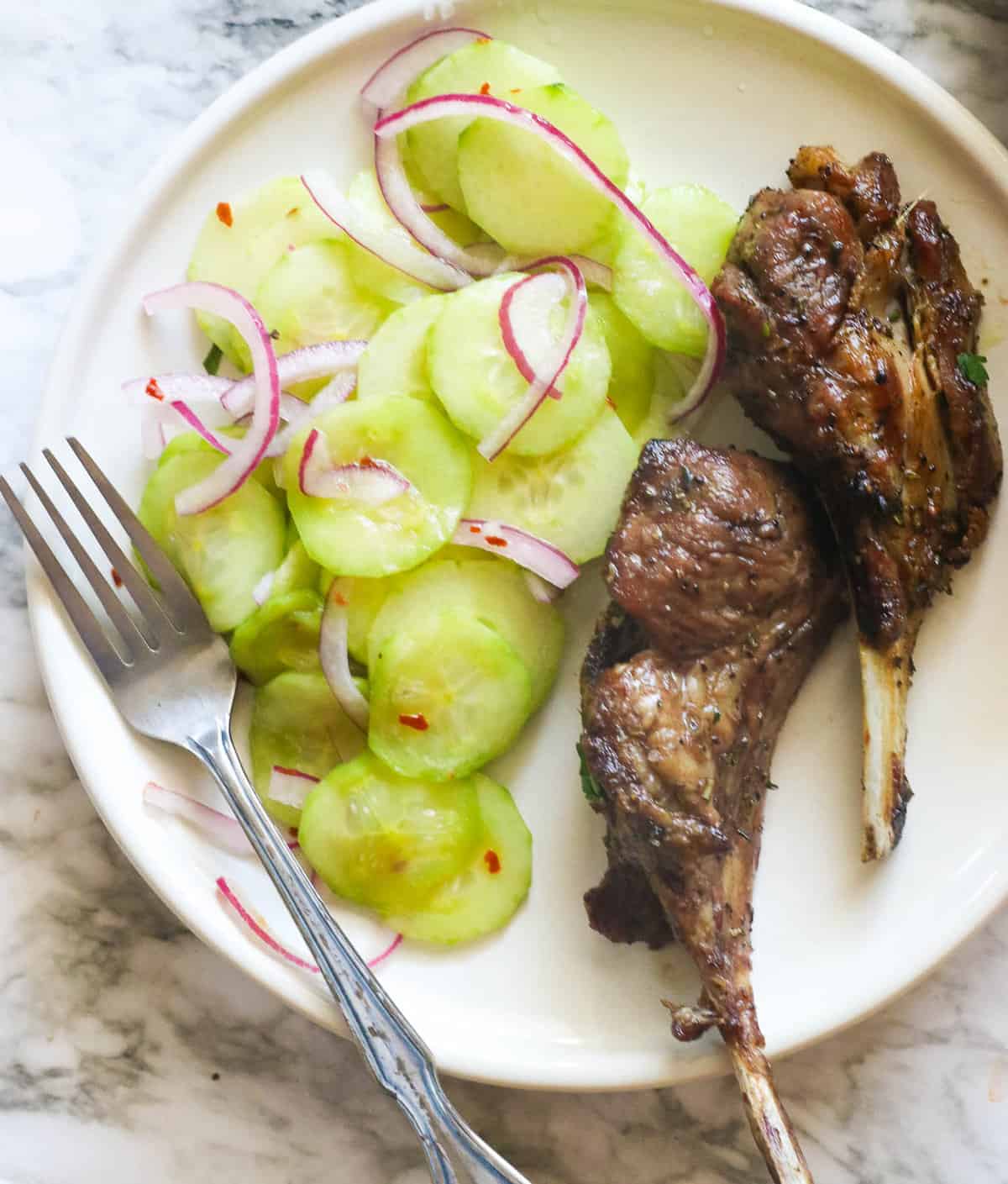 Serving cucumber and onion salad with grilled lamb chops
