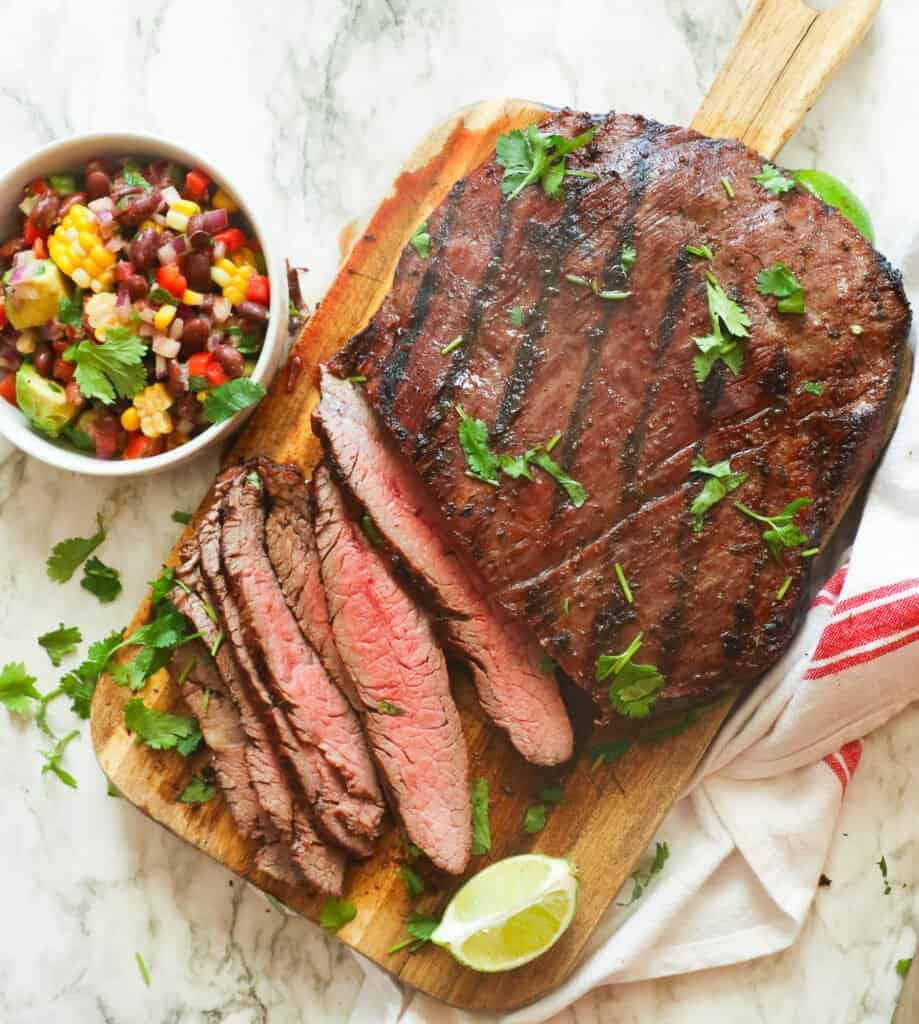 Sliced grilled flank steak with salad