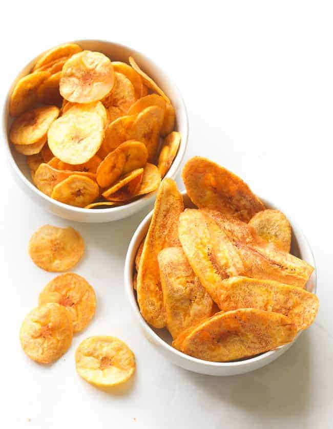 Two bowls of plantain chips, one sliced crossways and one sliced on a diagonal