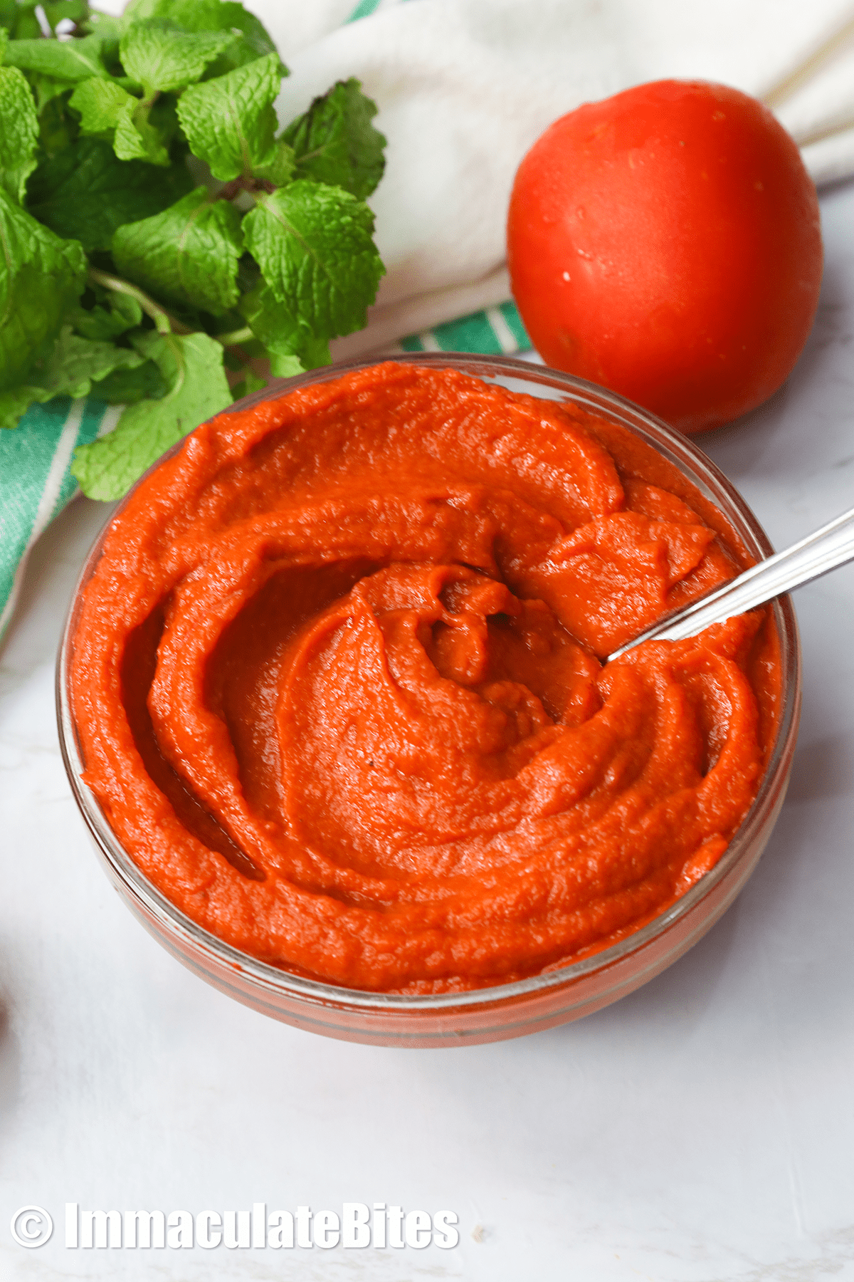 Tomato paste in a clear bowl with a spoon