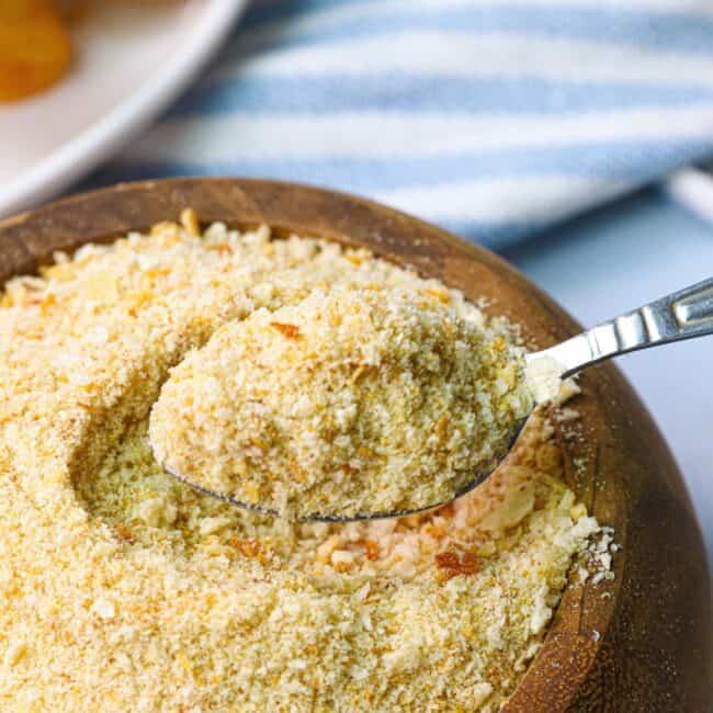 A wooden bowl of homemade breadcrumbs with a spoon