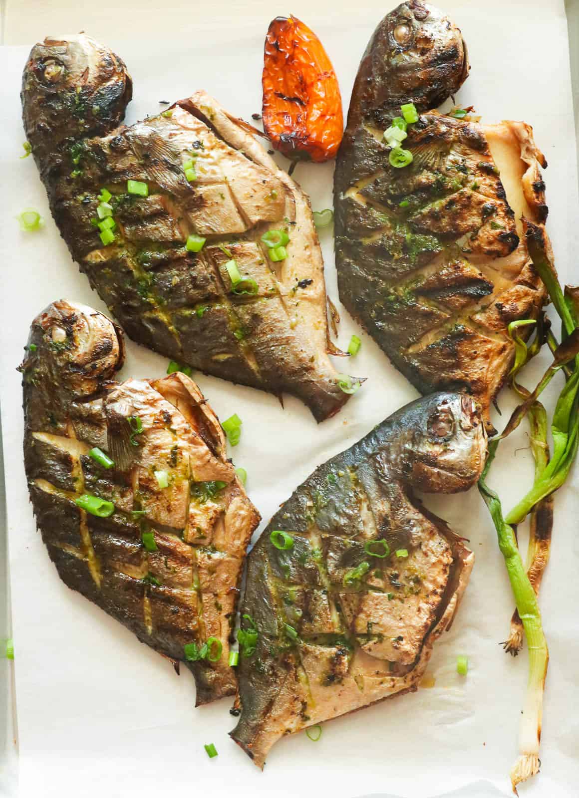 Grilled Pompano Fish garnished with sliced green onions.