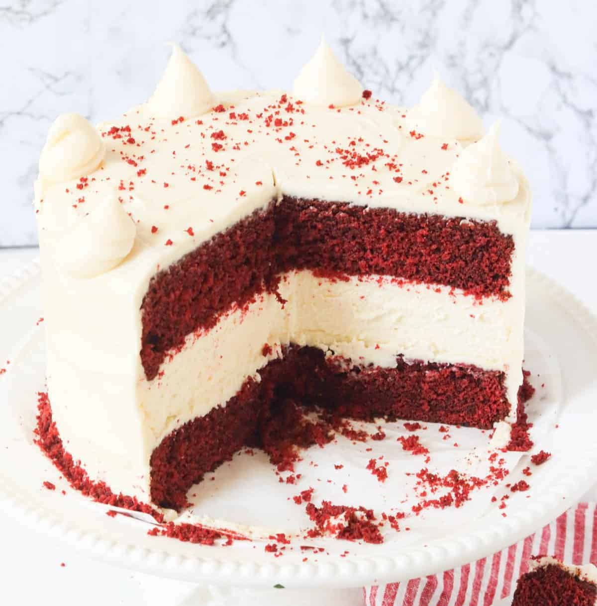 Red velvet cheesecake on a white cake platter with slices already served