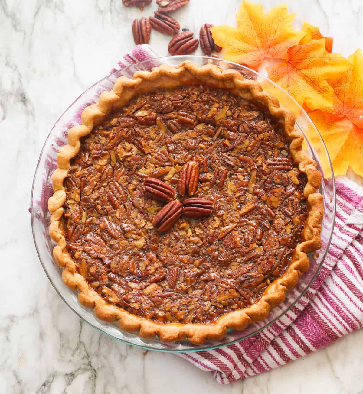 A whole pecan pie with fall decoration in the background