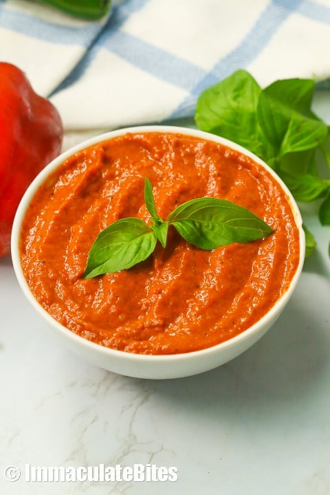 Roasted red pepper sauce topped with fresh basil leaves.