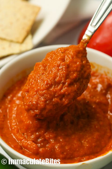 Lifting a spoon filled with roasted red pepper sauce