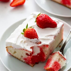 A slice of strawberry poke cake on a white plate