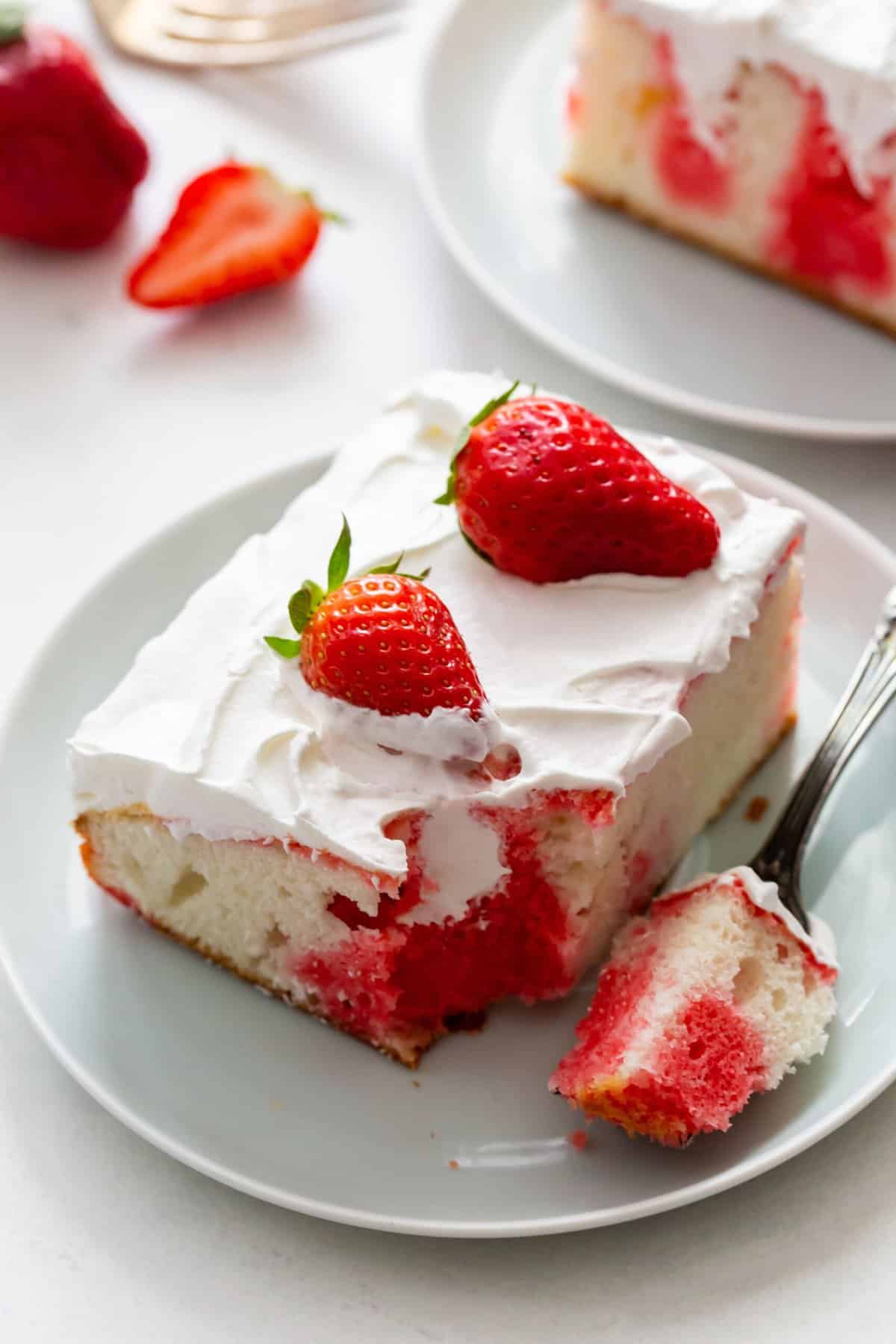 A slice of strawberry poke cake on a white plate