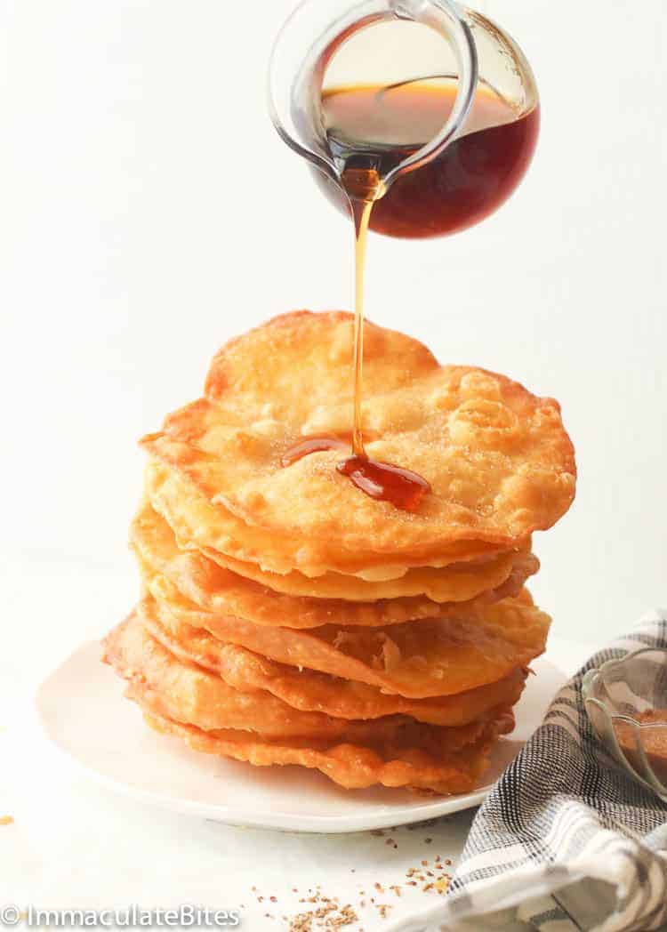 A stack of bunuelos drizzled with a sweet sauce.