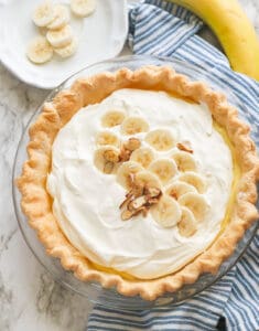 A whole banana cream pie topped with sliced bananas