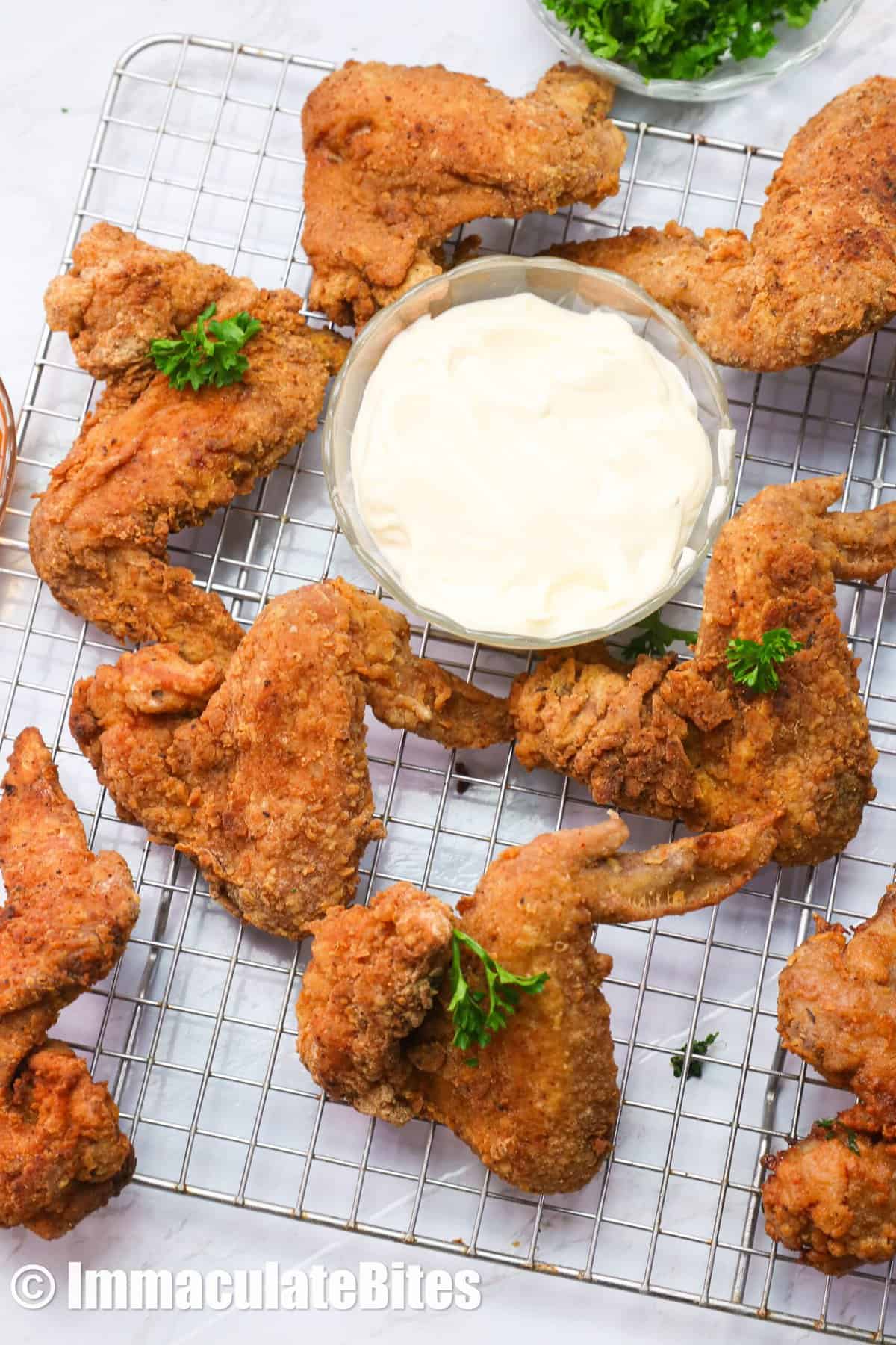Fried chicken wings on a rack with ranch dressing