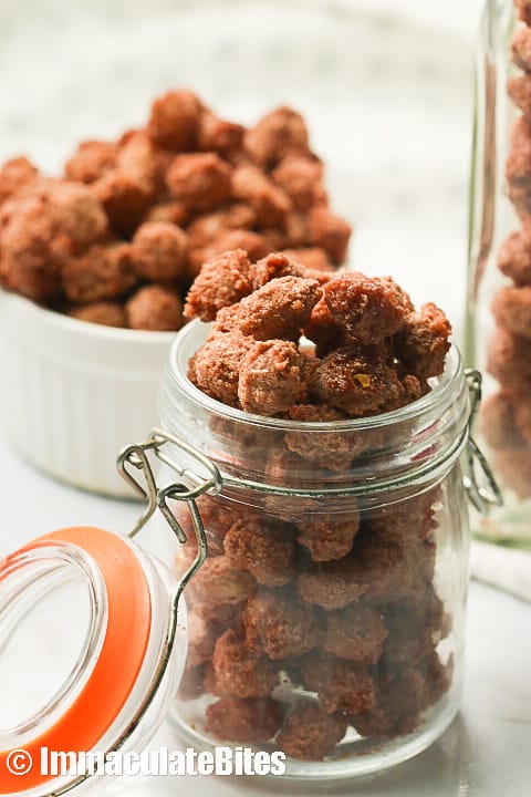A jar filled with candied peanuts with a bowl of more in the background
