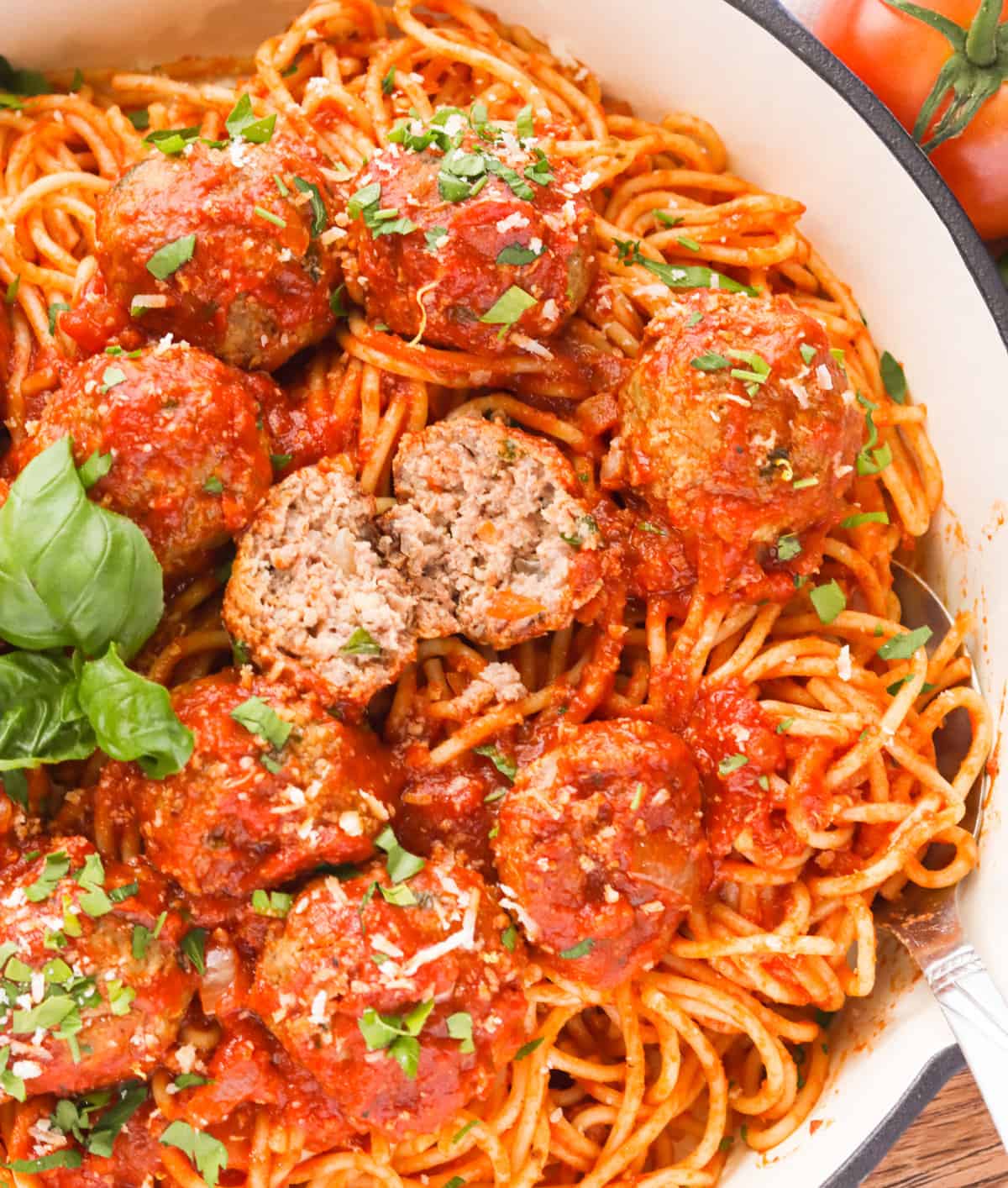 A bowl of spaghetti and meatballs with an inside shot of the meatball