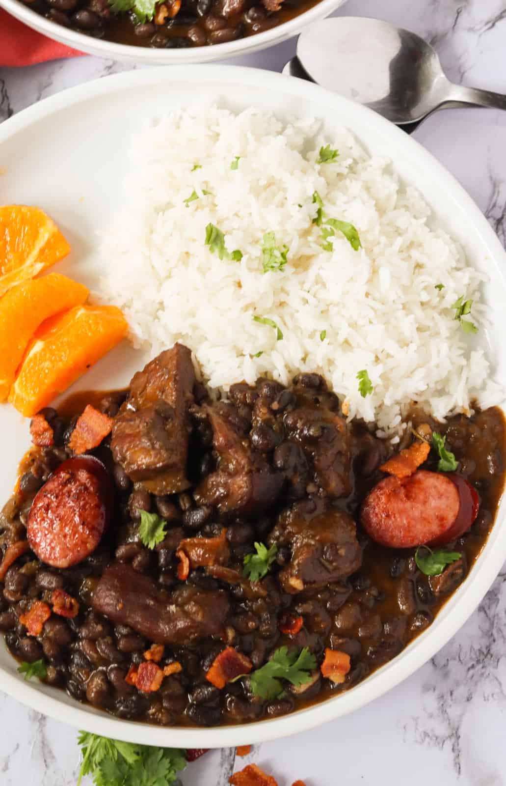 Feijoada served on a plate with white rice and orange slices