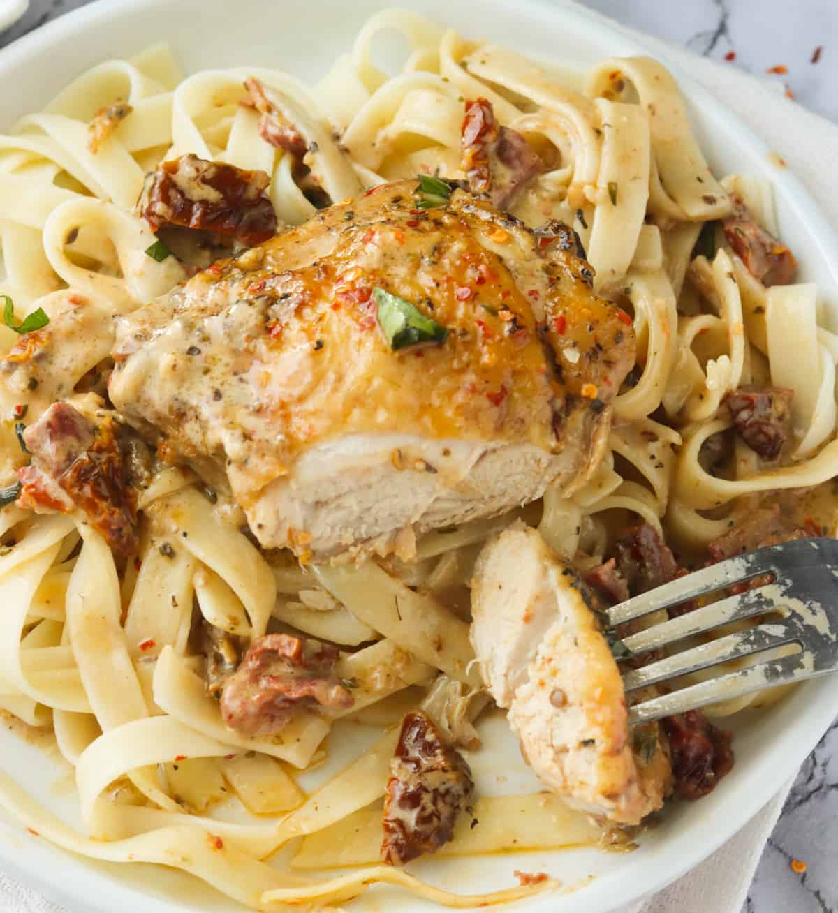 Marry Me Chicken over pasta cut with a fork for an inside view