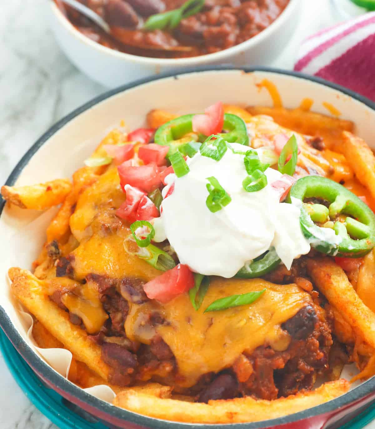Chili cheese fries topped with sour cream, diced tomatoes, and jalapenos