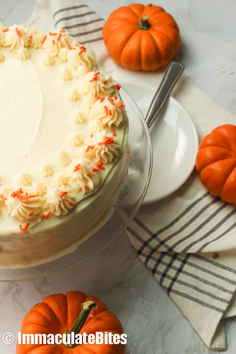 A delicious pumpkin cake with cute mini pumpkins in the background