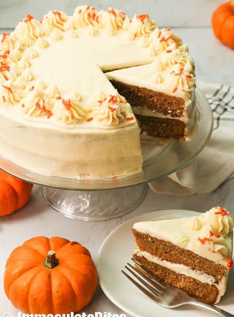 Pumpkin Cake with a slice served and cute mini pumpkins in the foreground