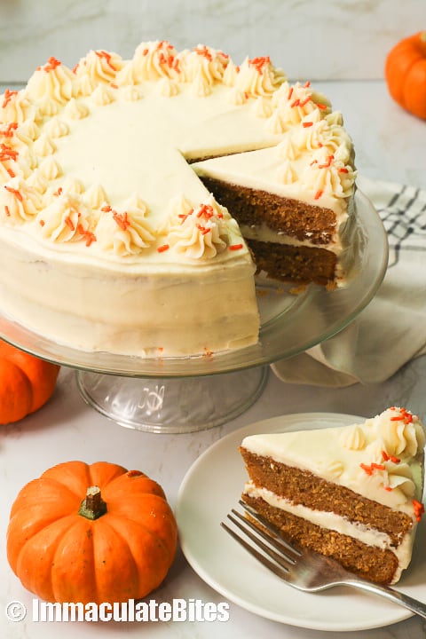 Pumpkin Cake with a slice served and cute mini pumpkins in the foreground