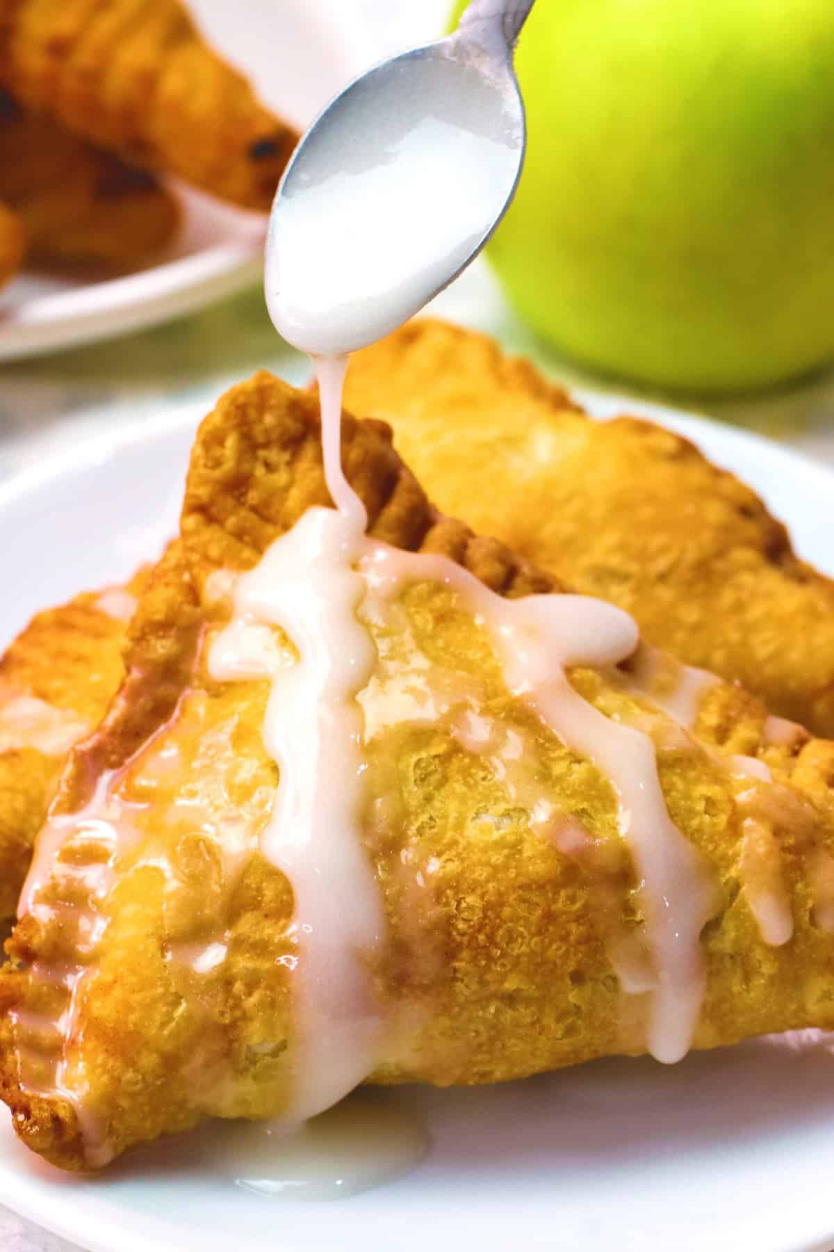 Drizzling glaze over slightly cooled personal apple pies.