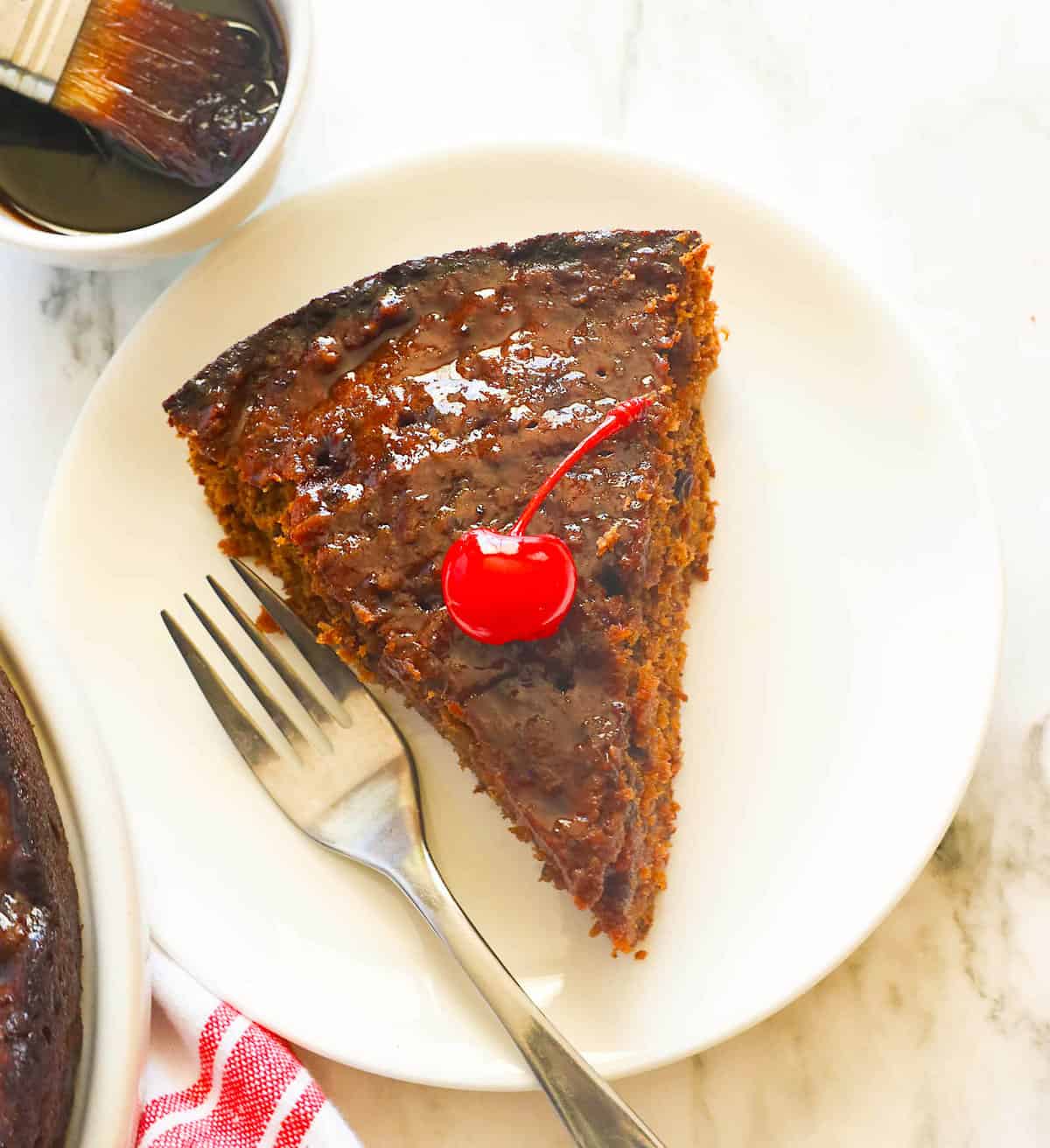 A decadent slice of Caribbean black cake with a cherry on top