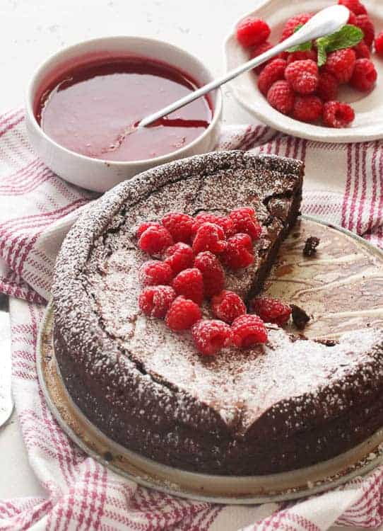 Topping a decadent flourless chocolate cake with raspberry sauce