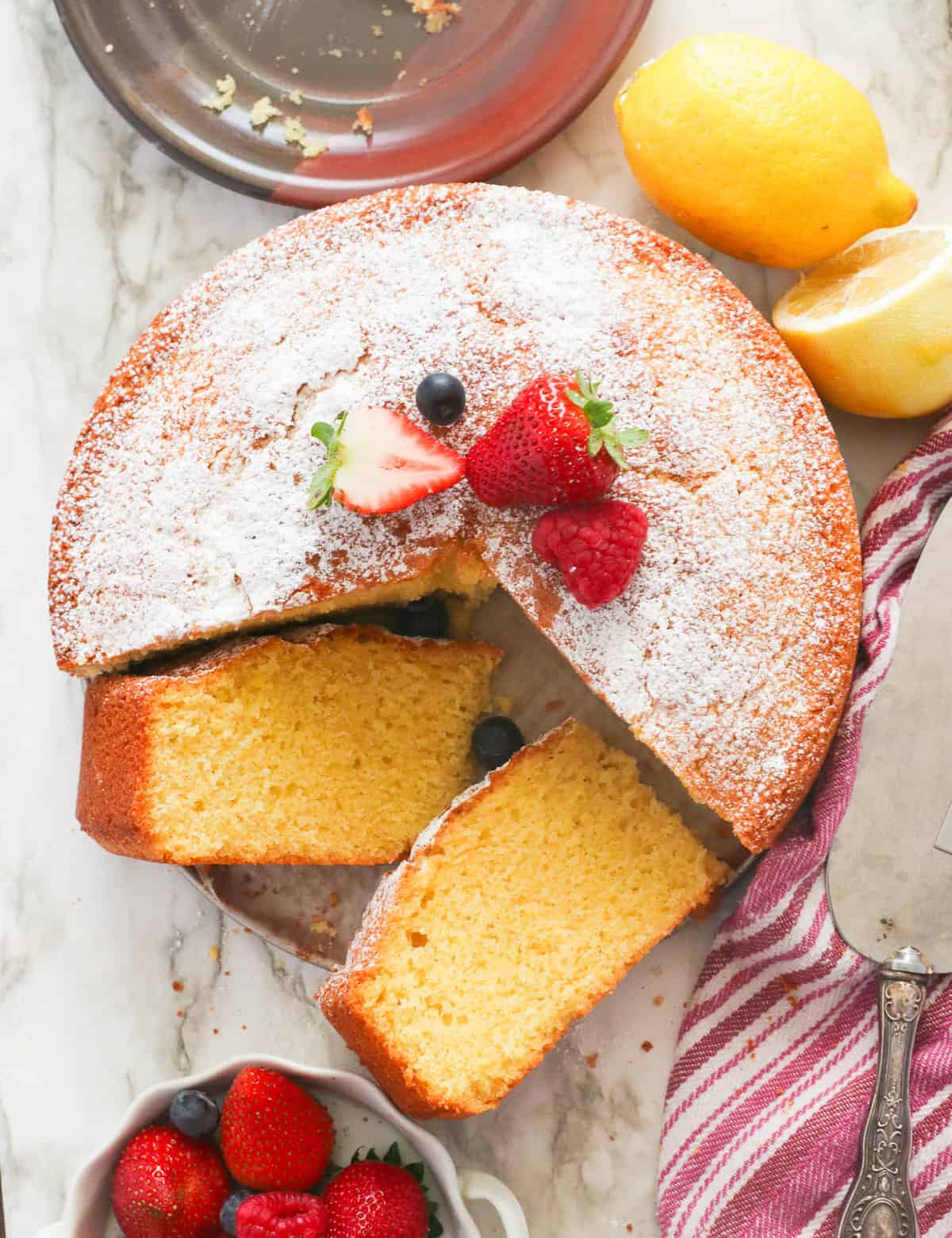 Trancher un gâteau à l'huile d'olive citronnée et servir avec des fruits