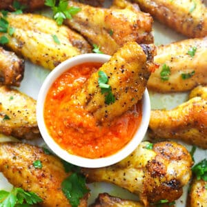 Dipping insanely good lemon pepper chicken wings in hot sauce