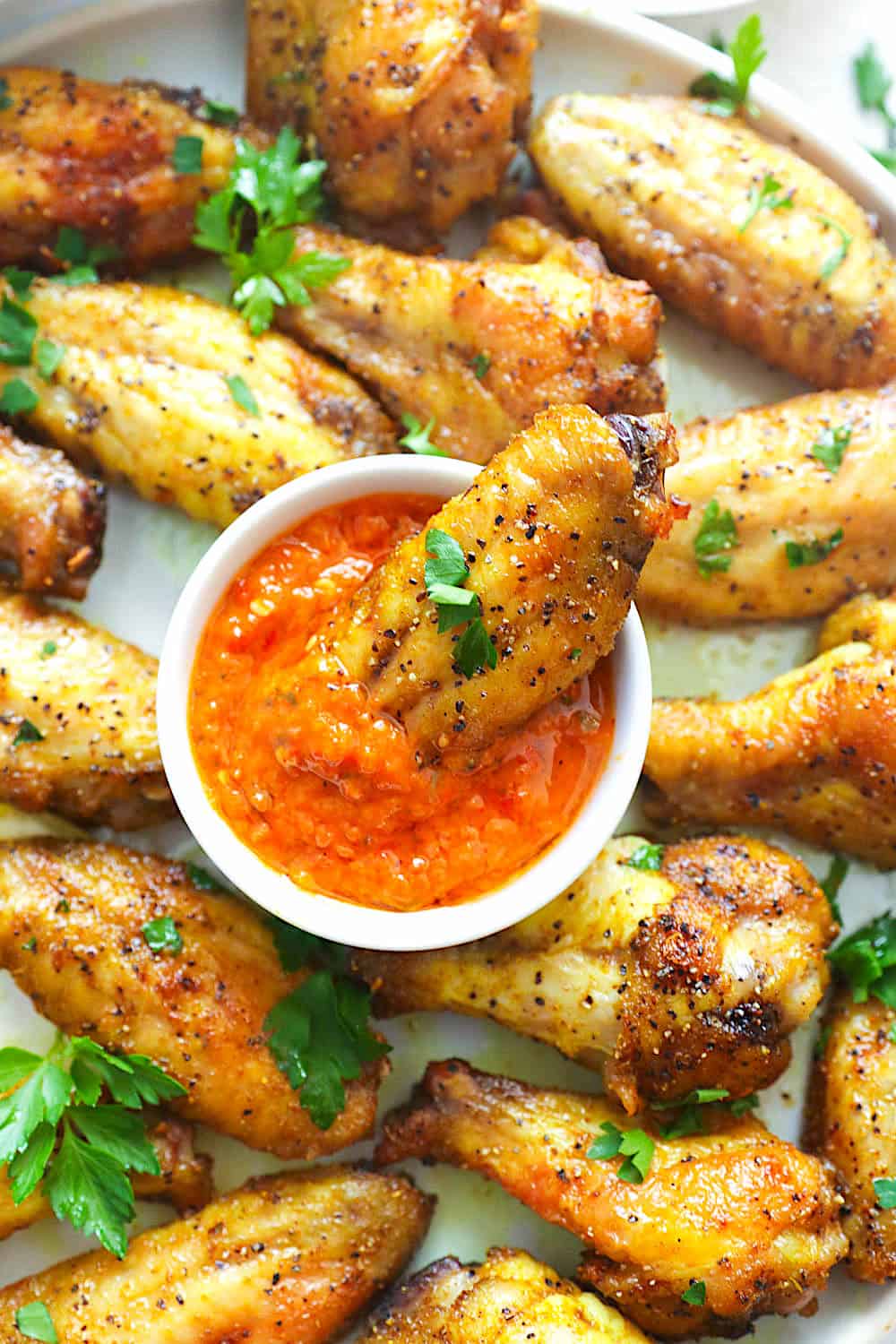 Dipping insanely good lemon pepper chicken wings in hot sauce