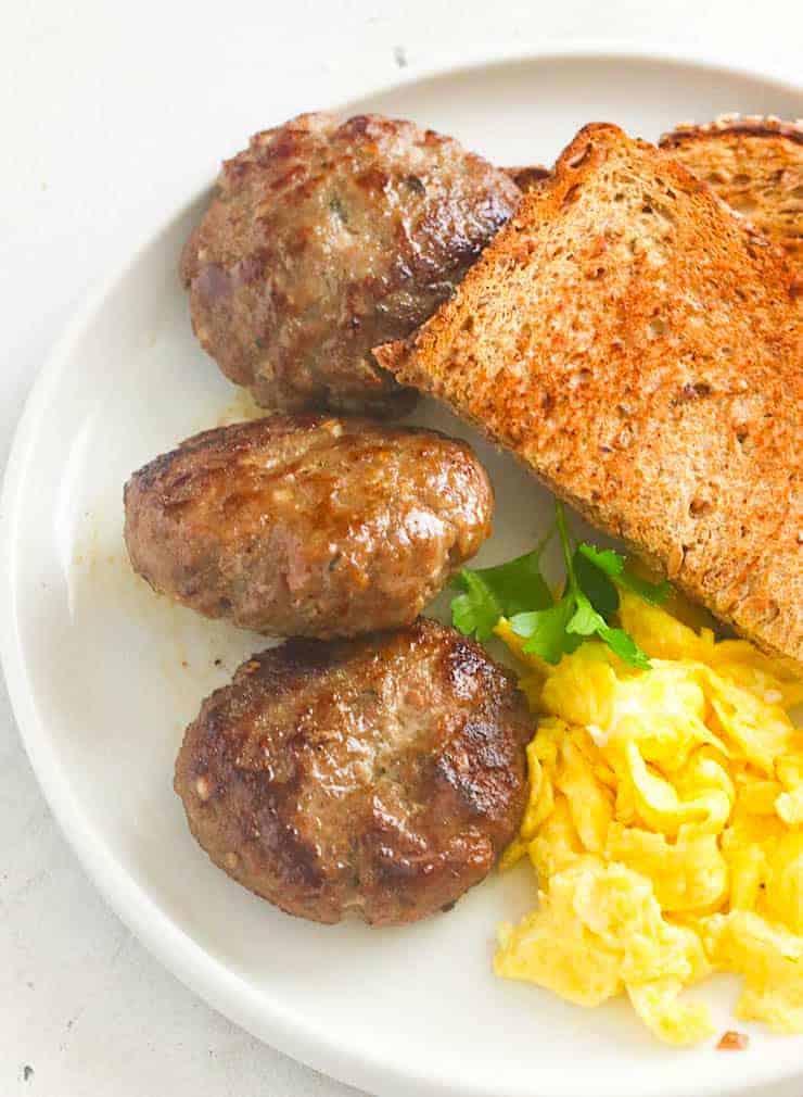 Appréciant la saucisse de petit déjeuner de dinde avec des oeufs et du pain grillé