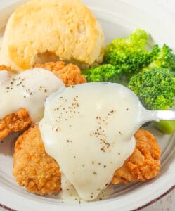 Slathering tasty white gravy over fried chicken and biscuits