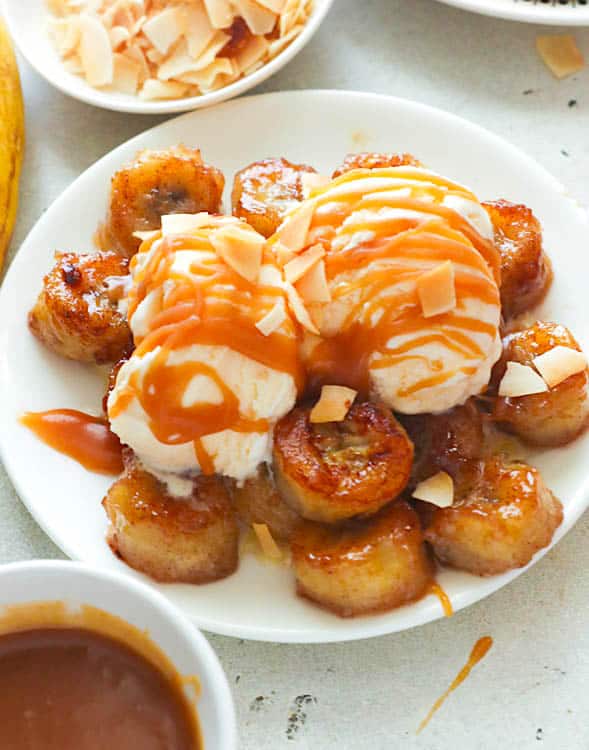 Golden crispy fried bananas topped with ice cream, homemade caramel, and toasted coconut