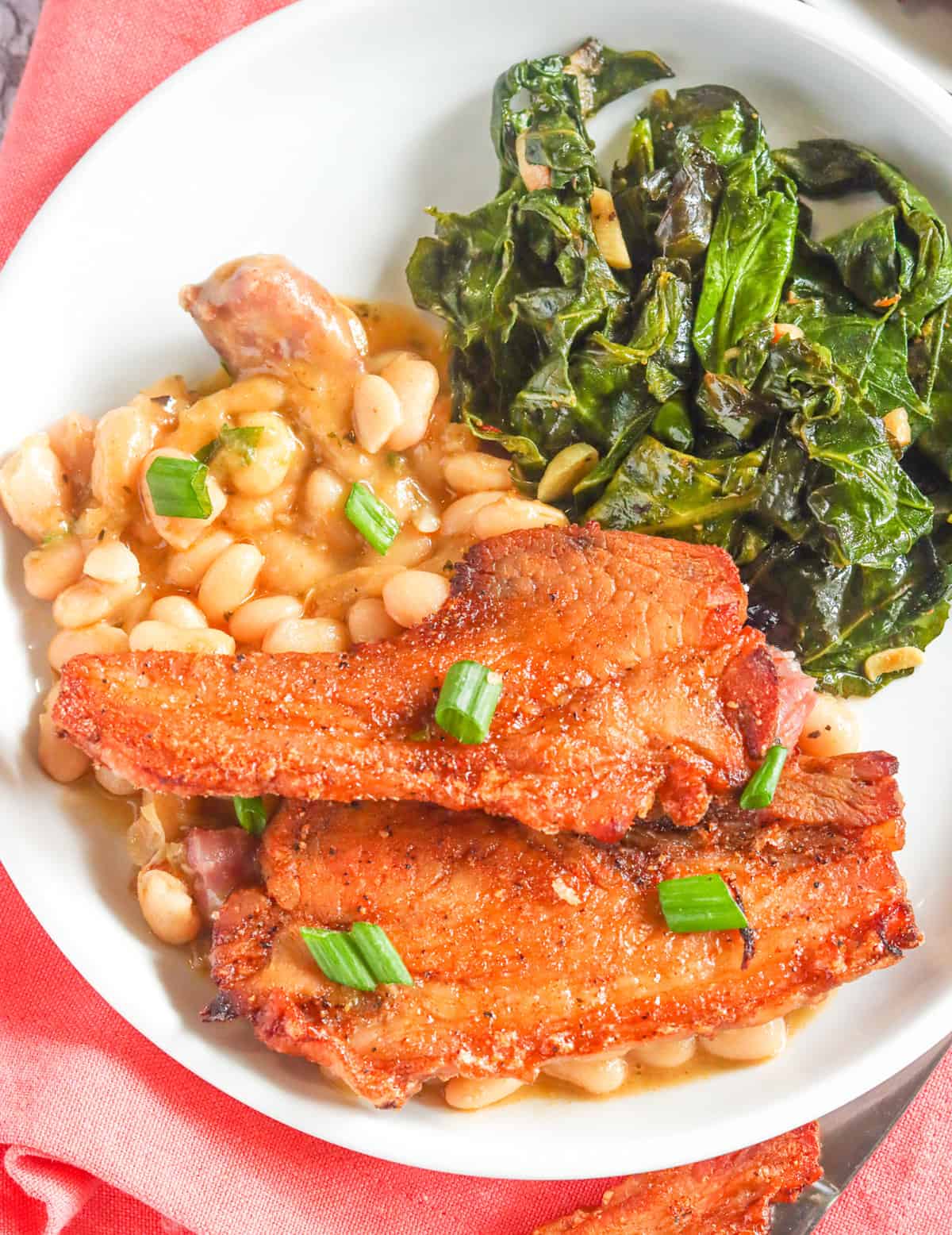 Crispy pork jowl with beans and collard greens