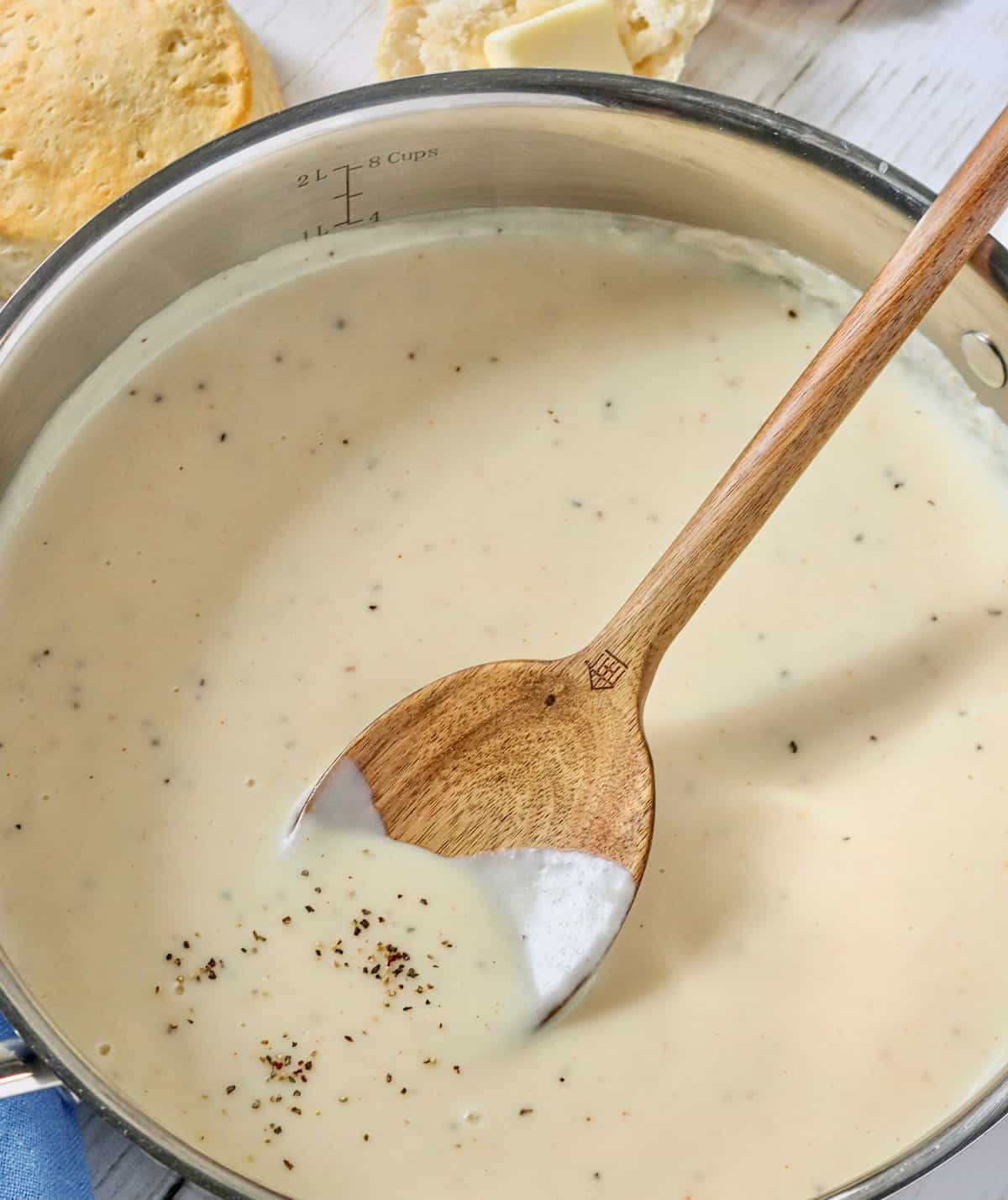 Taking milk-based gravy off the stove and getting ready to serve it with biscuits.