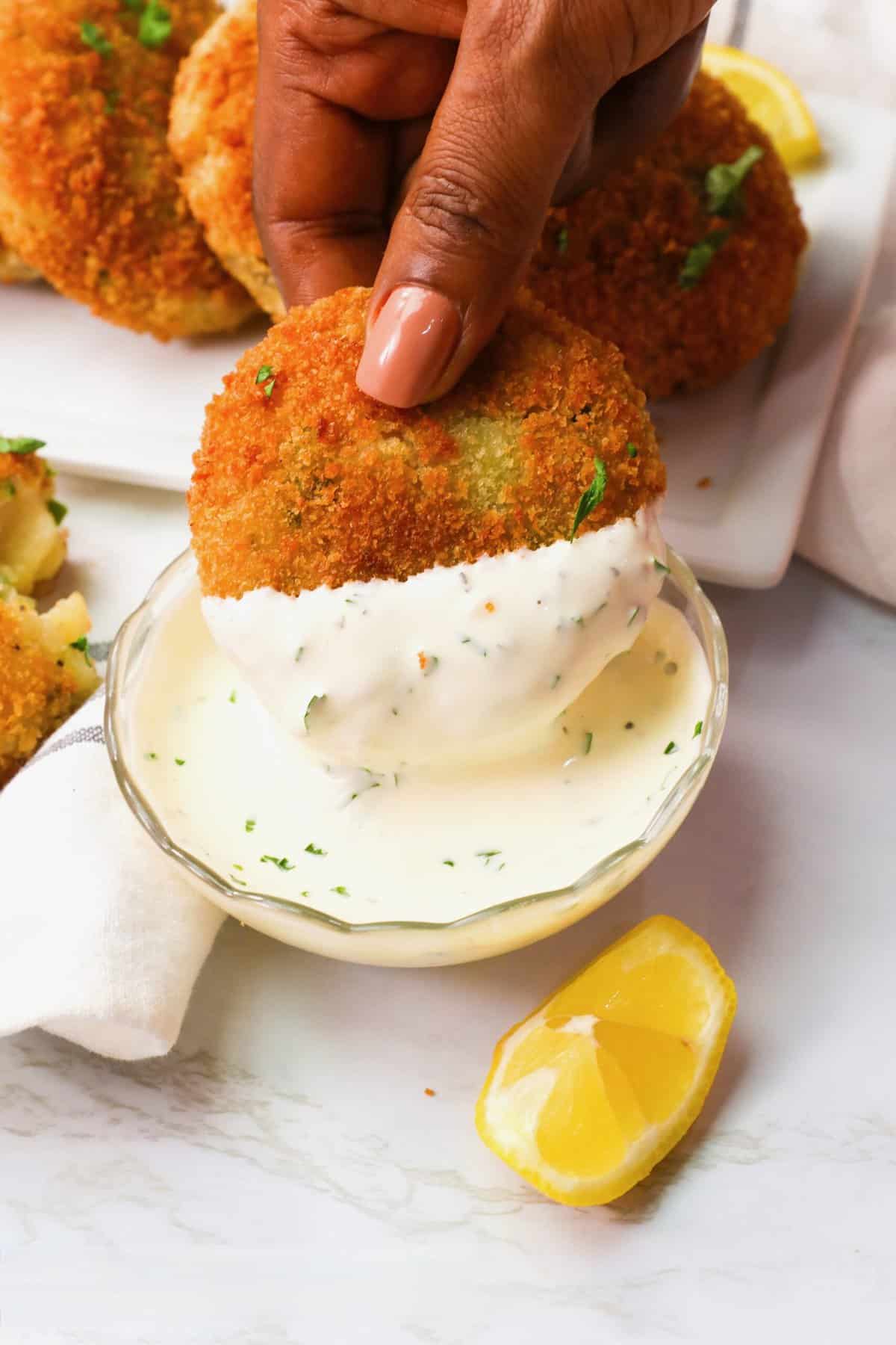Dipping delicate fish cakes into homemade tartar sauce