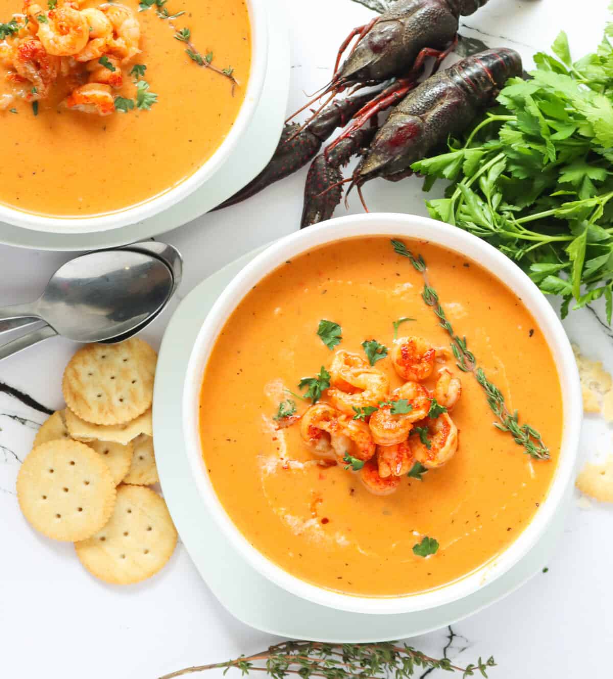 Two bowls of creamy, hot crawfish bisque ready to enjoy with crayfish in the background