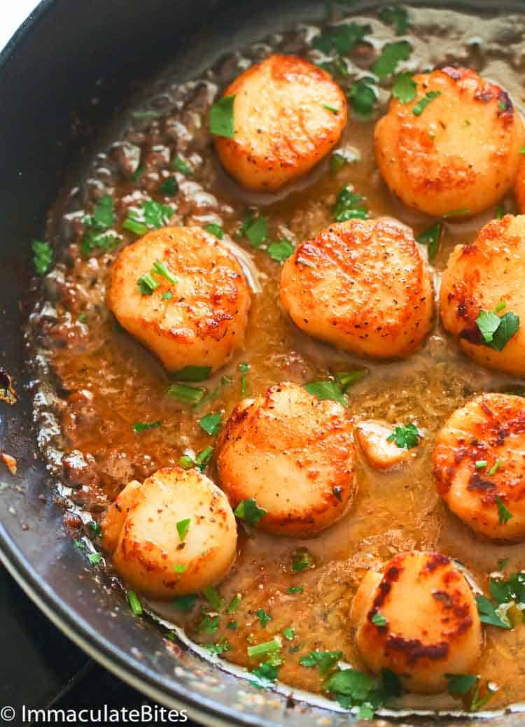 Delicious scallops searing in a smoking hot pan