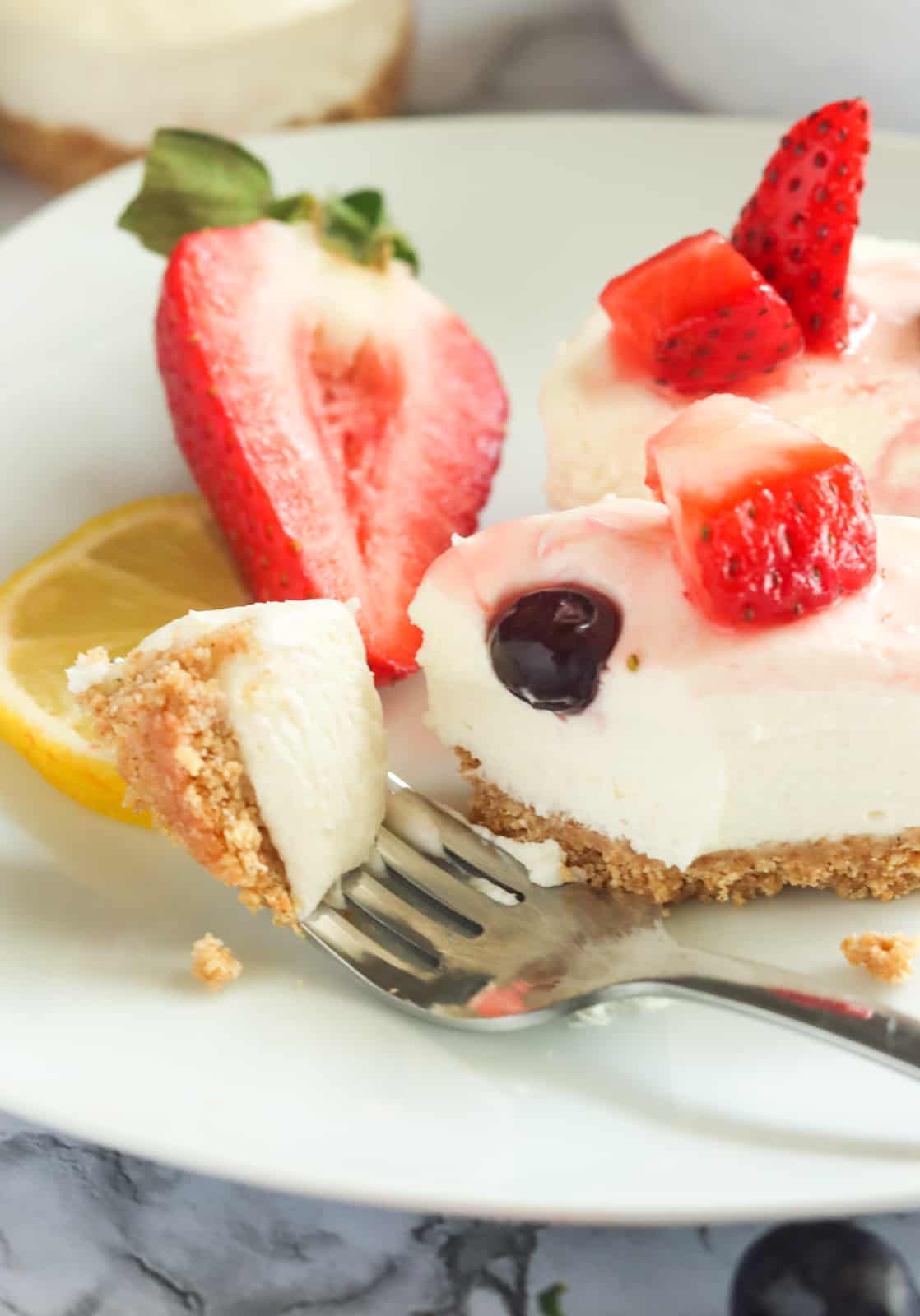 Slicing off a bite of insanely delicious no-bake cheesecake bites with berries and cherries