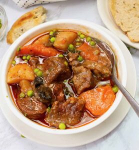 Insanely delicious slow cooker lamb stew in a white bowl with homemade bread